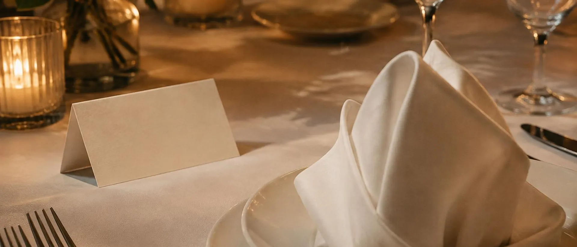 A blank ivory place card and folded napkin on white linen.